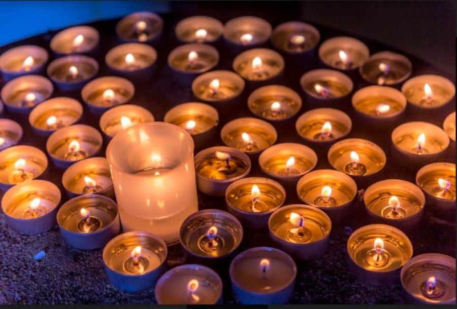 array of lit votive candles glowing