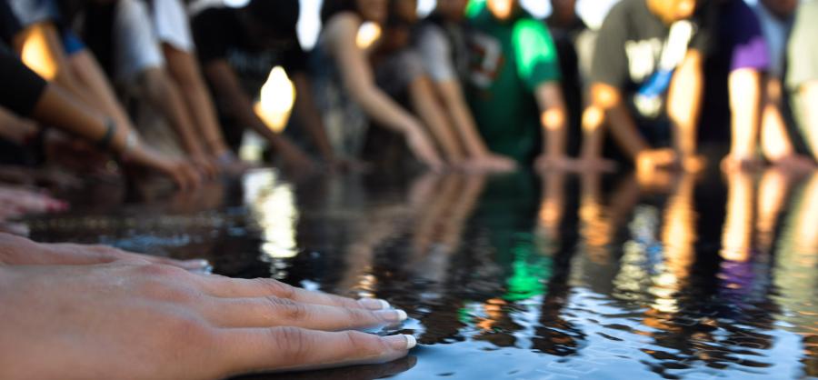 People standing around, with hands on the Civil Rights Memorial