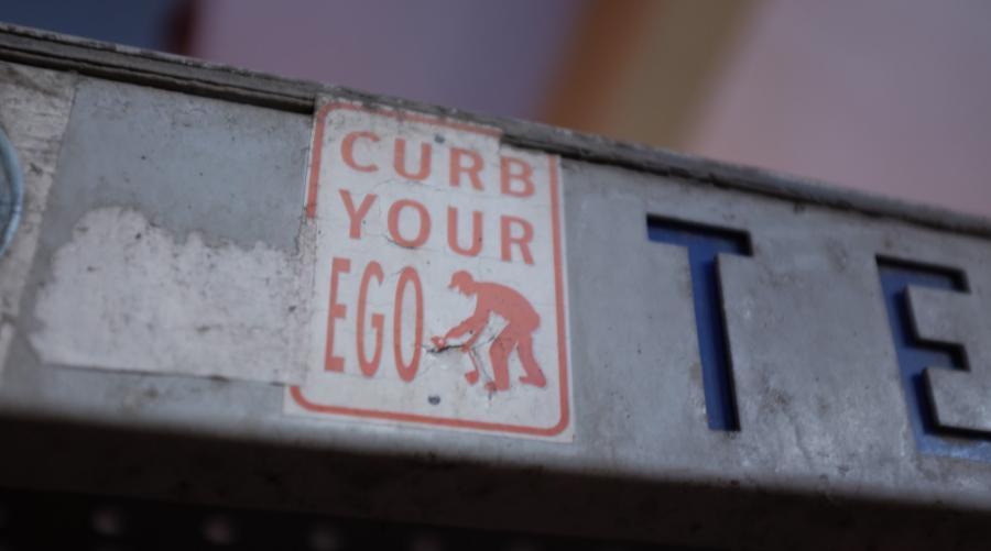 Sign with curb your ego in red and white lettering