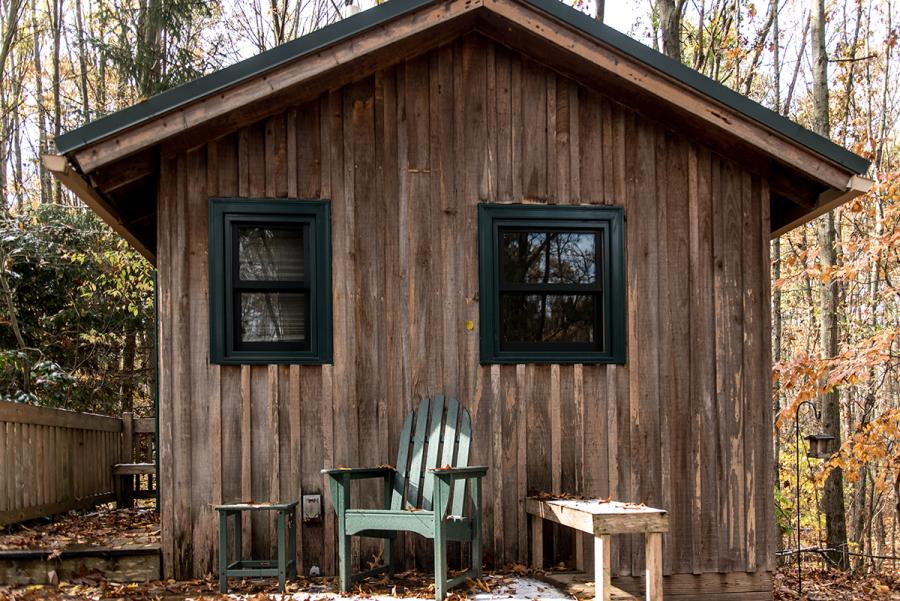 wooden cabin porch with chair and bench in woods