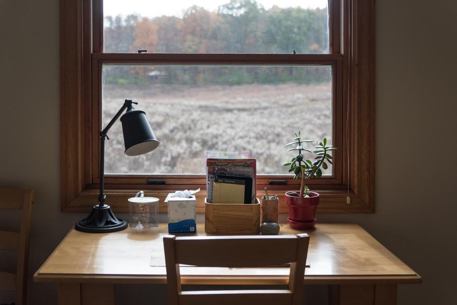desk with lamp looking over a field through the window