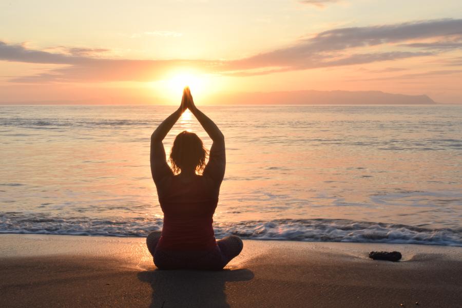 silhouette of seated yoga pose on beach at sunset