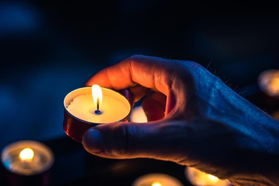 hand holding lit tea candle