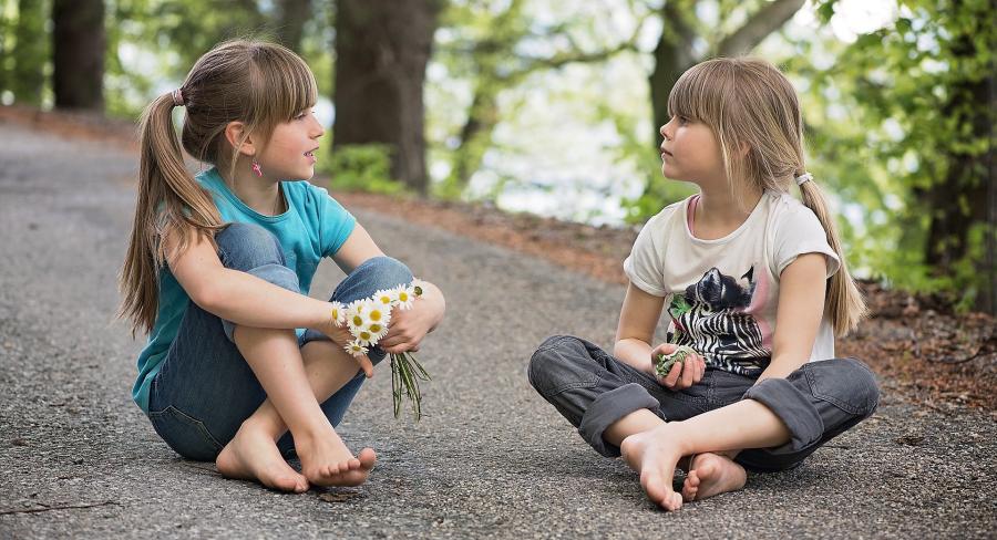 Two girls sitting on the ground talking