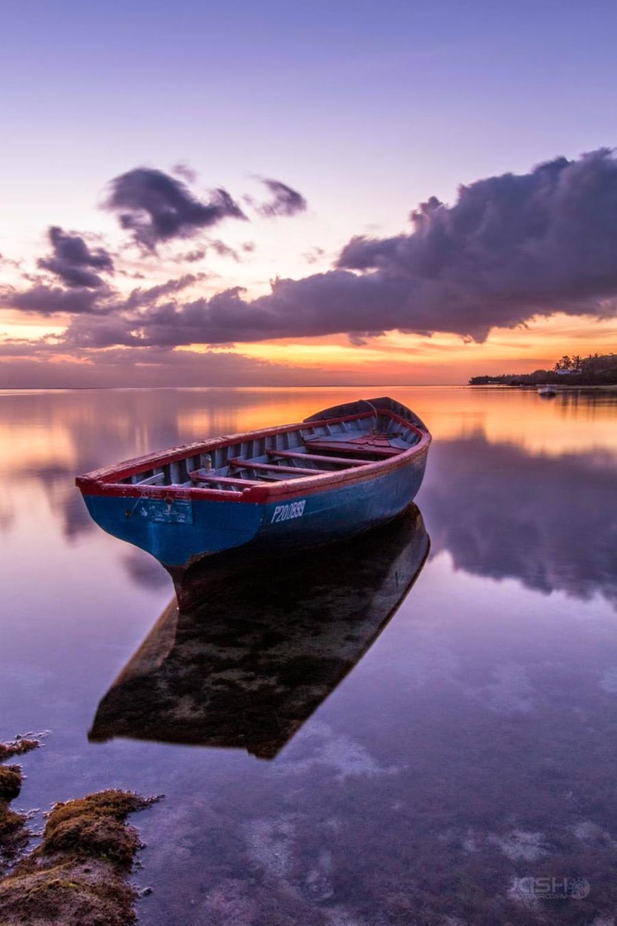 boat on calm water with sunset reflection