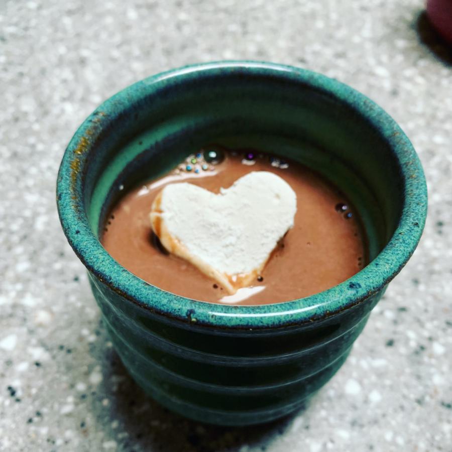 heart-shaped marshmallow in blue mug of hot cocoa