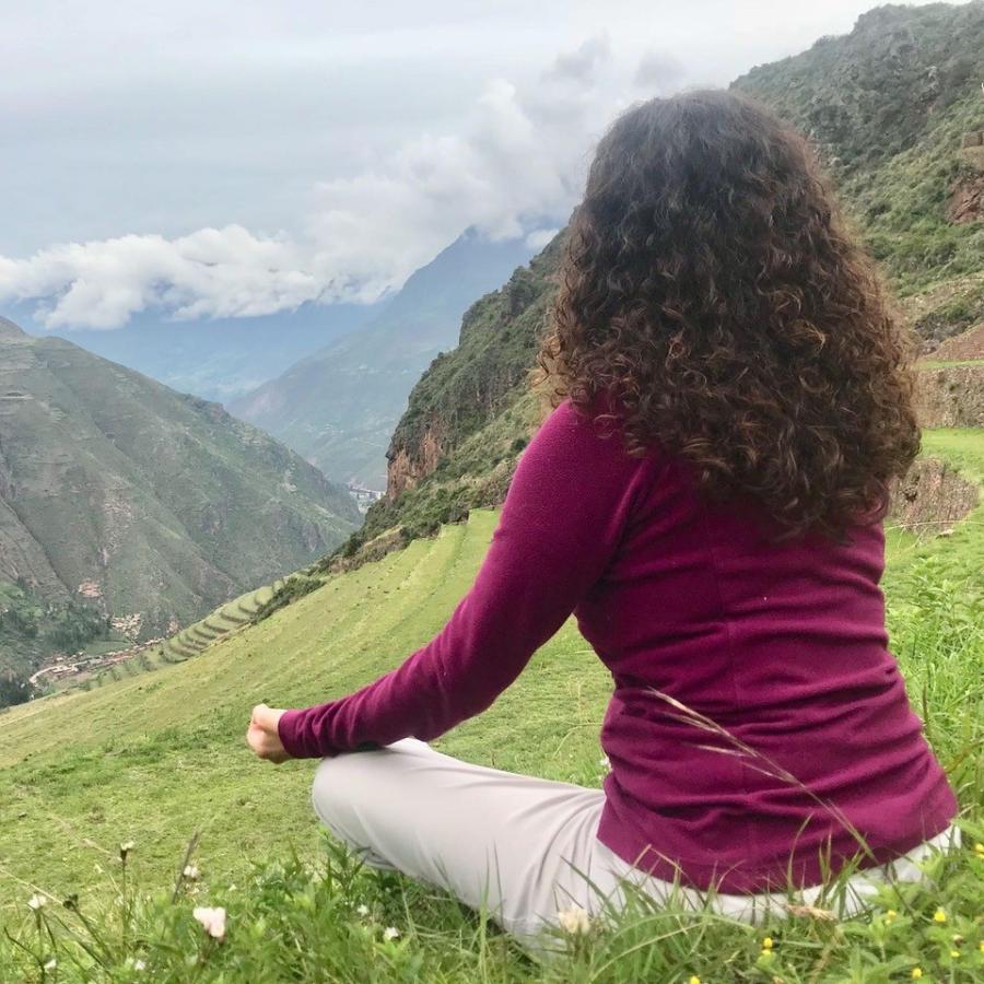 person sitting in meditation pose at the top of a mountain