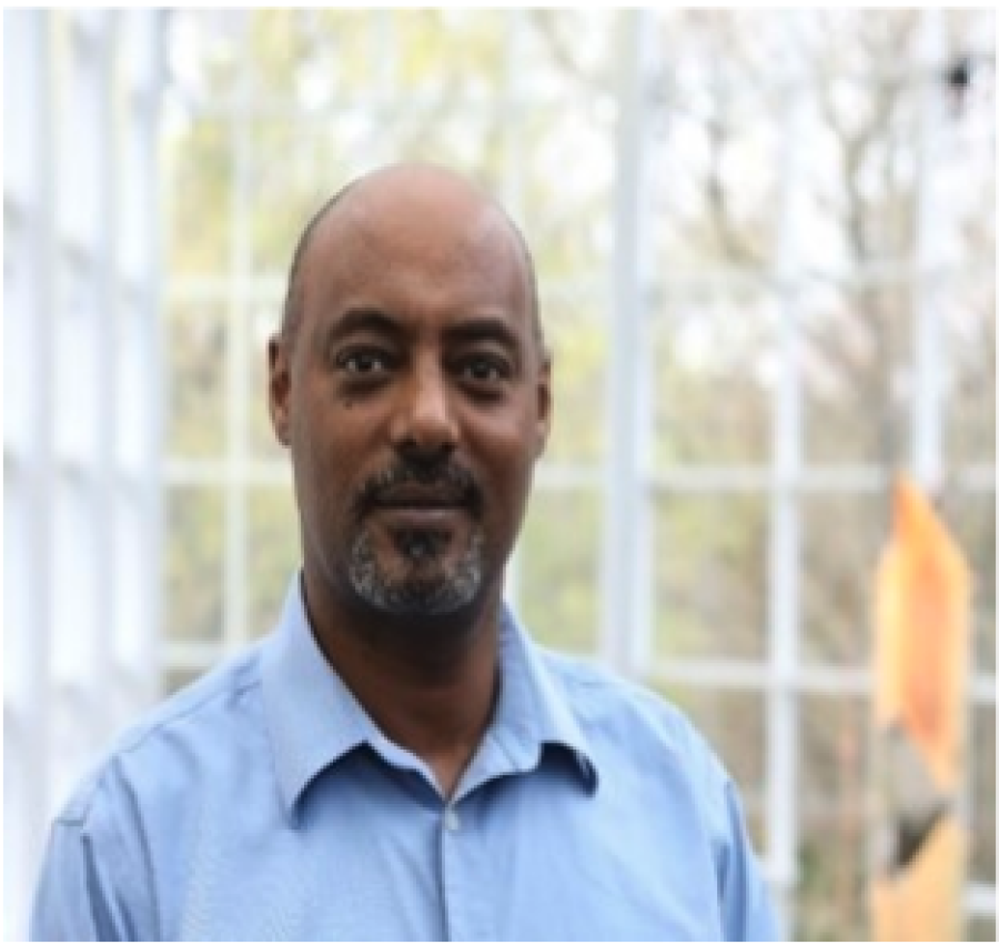 Male with bald head, facial hair wearing a blue button up shirt