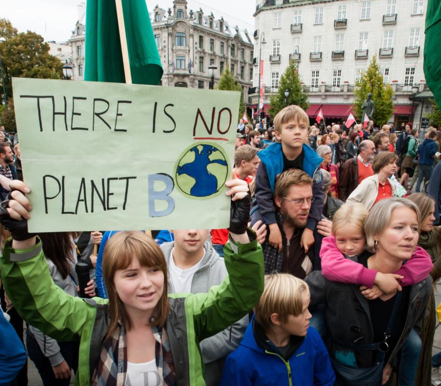 child holding "there is no planet B" sign at demonstration with family