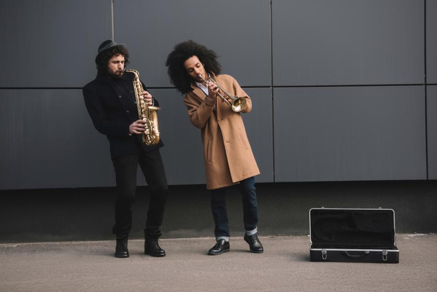 Two young men play sax and trumpet on the street