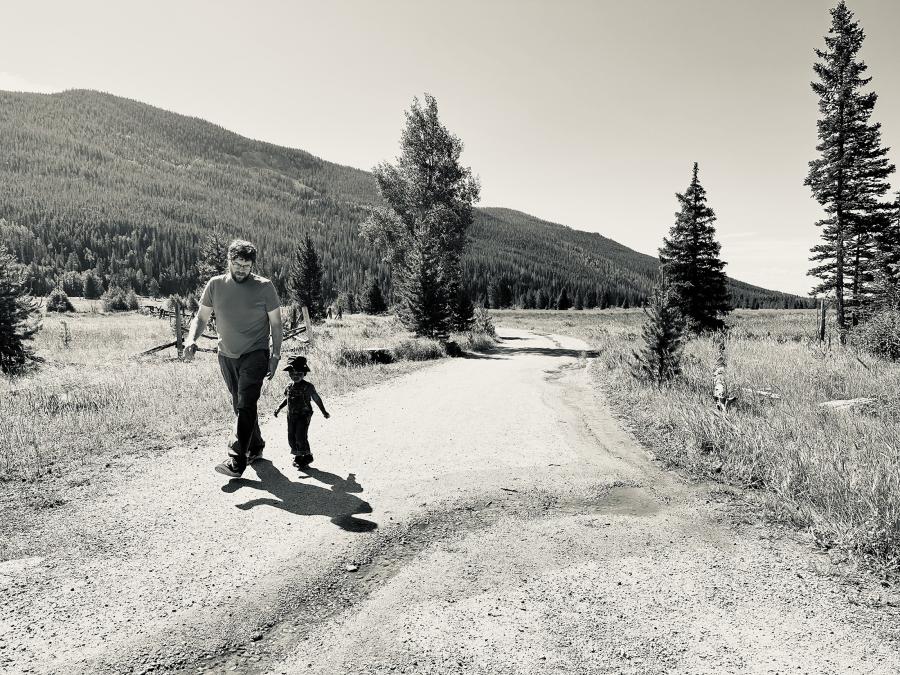 man and boy walk on a mountain road