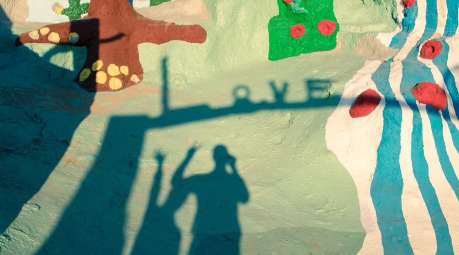 Silhouette of two people and the word love over colorful mural