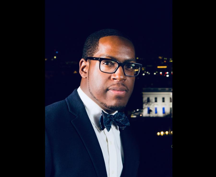 A black man with glasses wearing a suit and bow tie