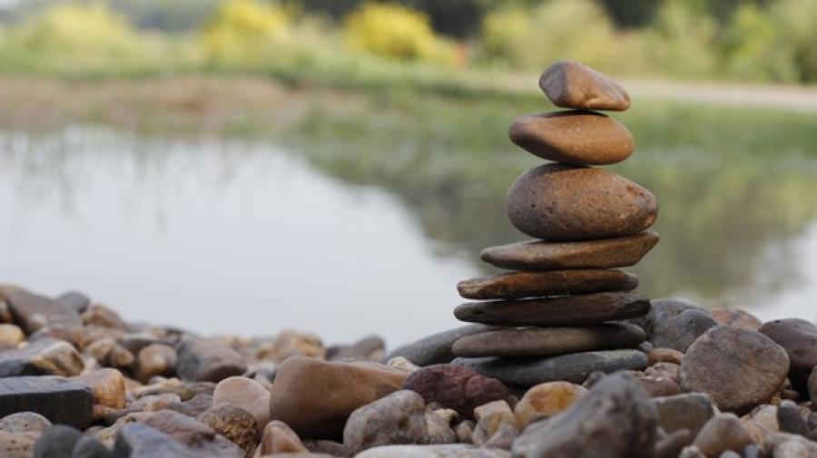 cairn of stones by water and green vegetation