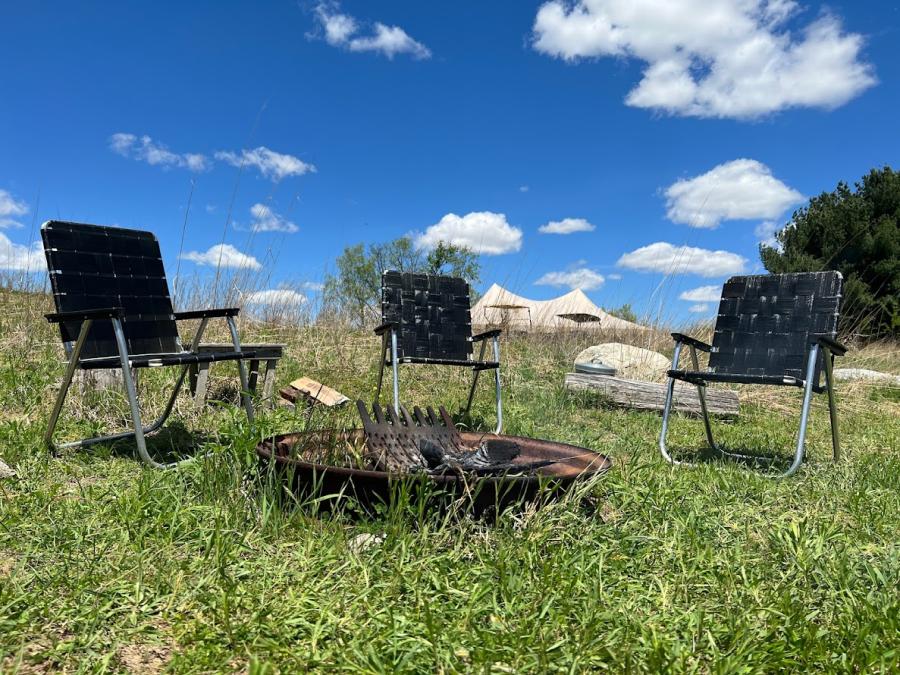 three black lawn chairs around a campfire with blue skies