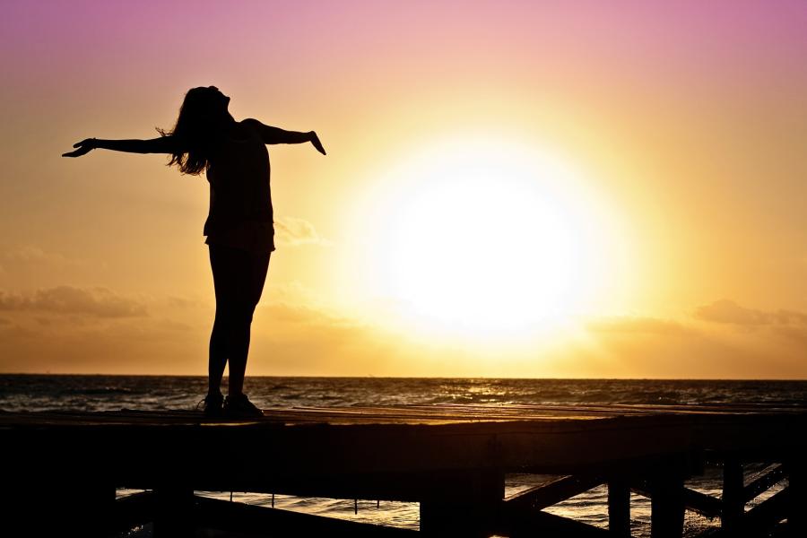 woman standing on windy pier with sunset in background