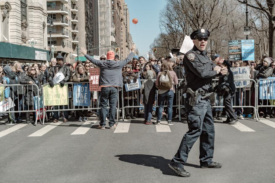 demonstrating crowd behind barrier with policman in foreground